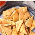 Up close image of pita chips on parchment-lined plate.