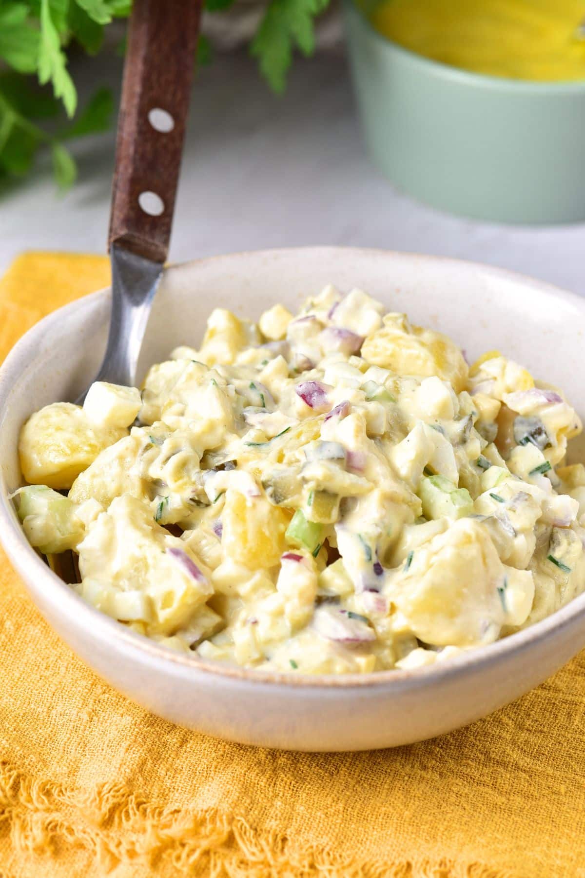 A spoon in a bowl of potato salad.