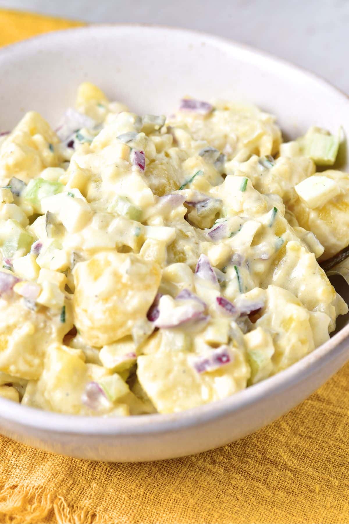 A bowl of gluten-free potato salad on yellow towel.