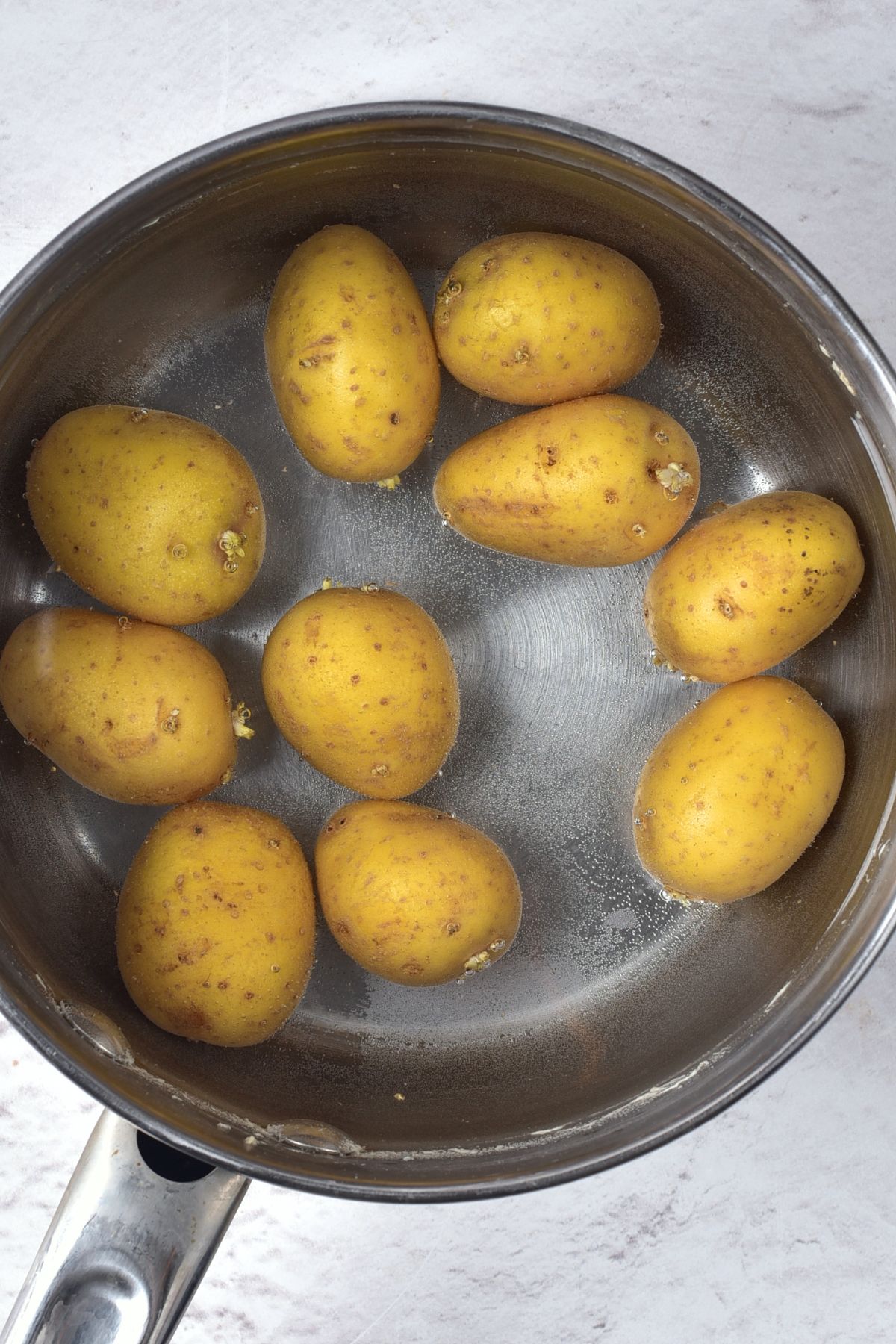 Boiling baby potatoes in a pot of water.