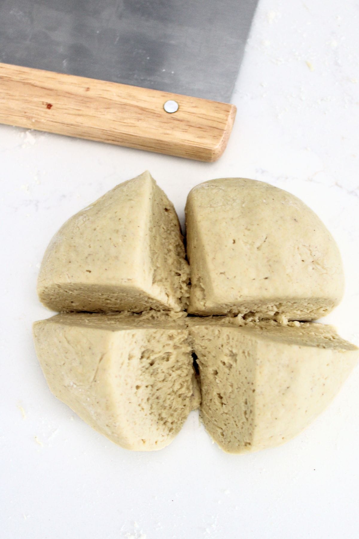 Cutting a ball of gf pretzel dough into 4 pieces