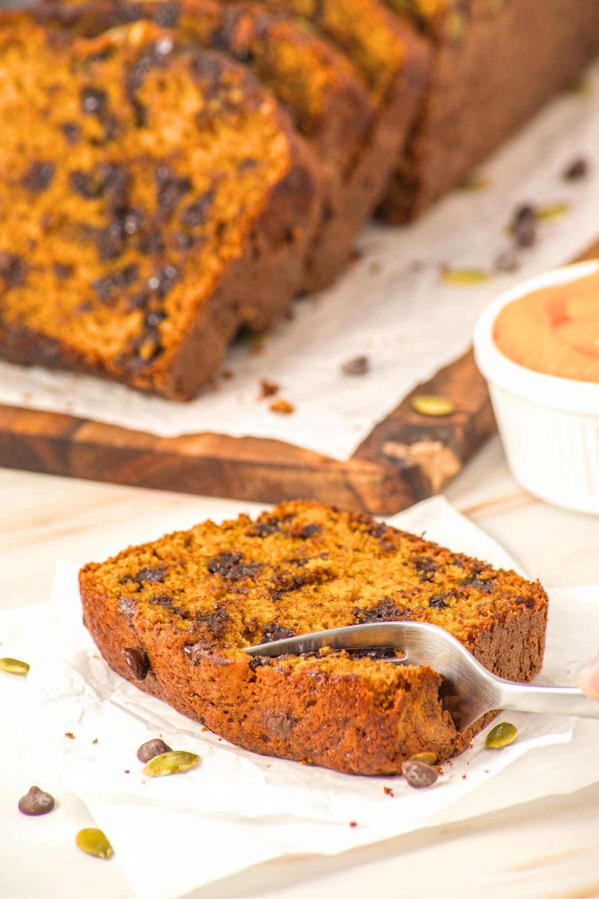 Fork cutting into a slice of pumpkin chocolate chip bread.