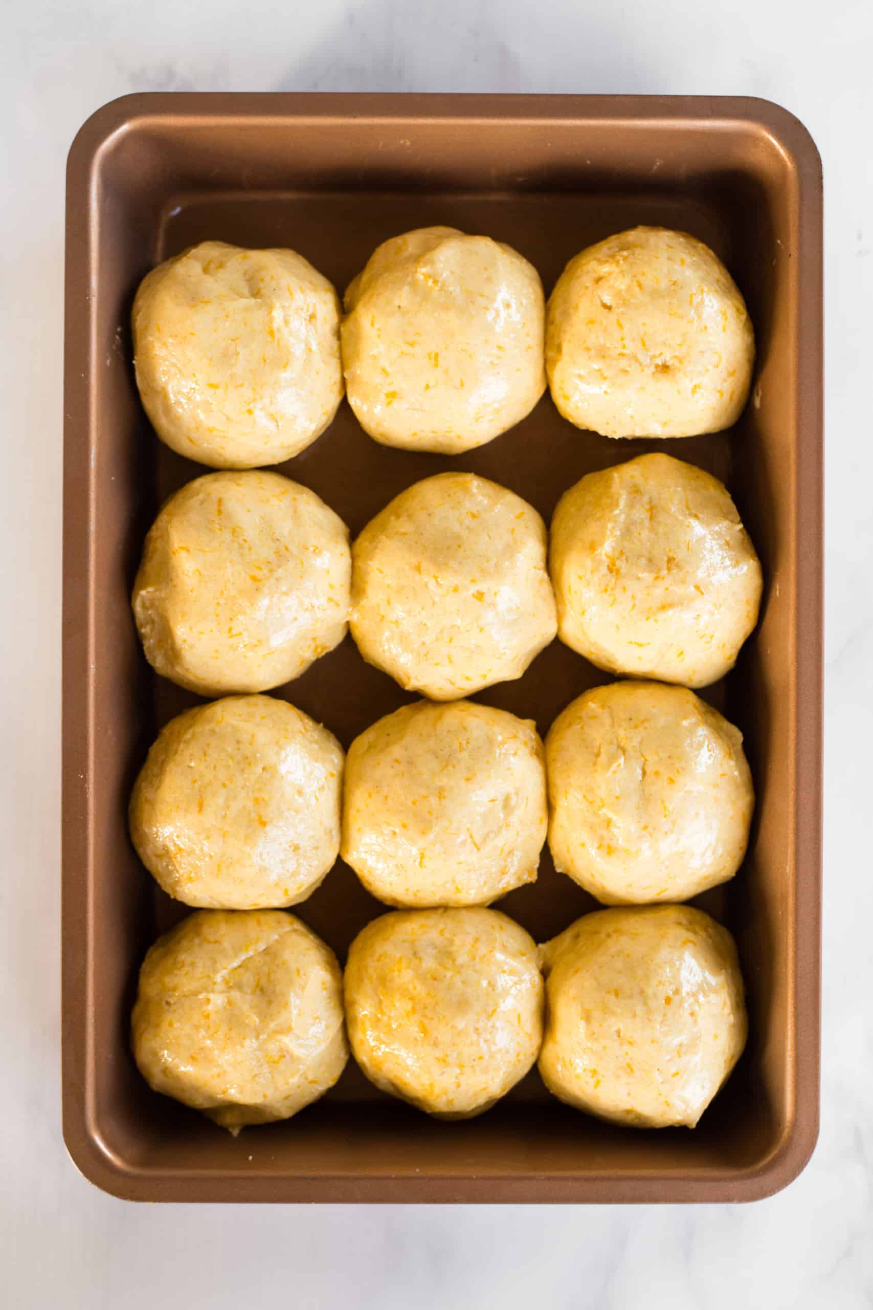 Balls of pumpkin bread dough in baking sheet.