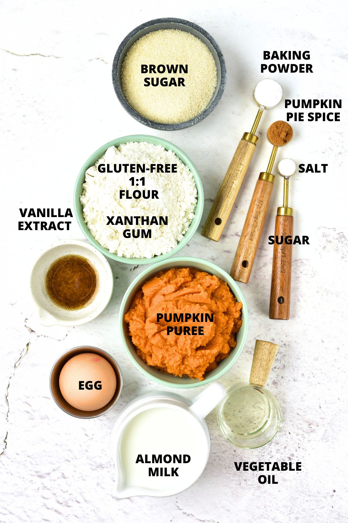 Top down view of ingredients of gluten-free pumpkin pancakes recipe laid out on marble board.