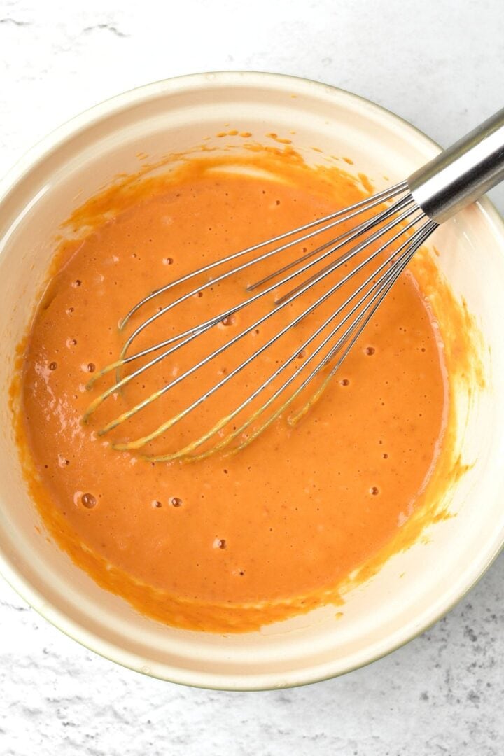 Whisking orange mixture in white bowl