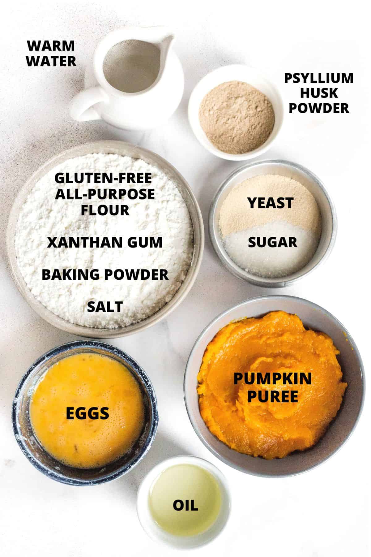 Ingredients required for gluten-free pumpkin dinner rolls recipe laid out on marble board.