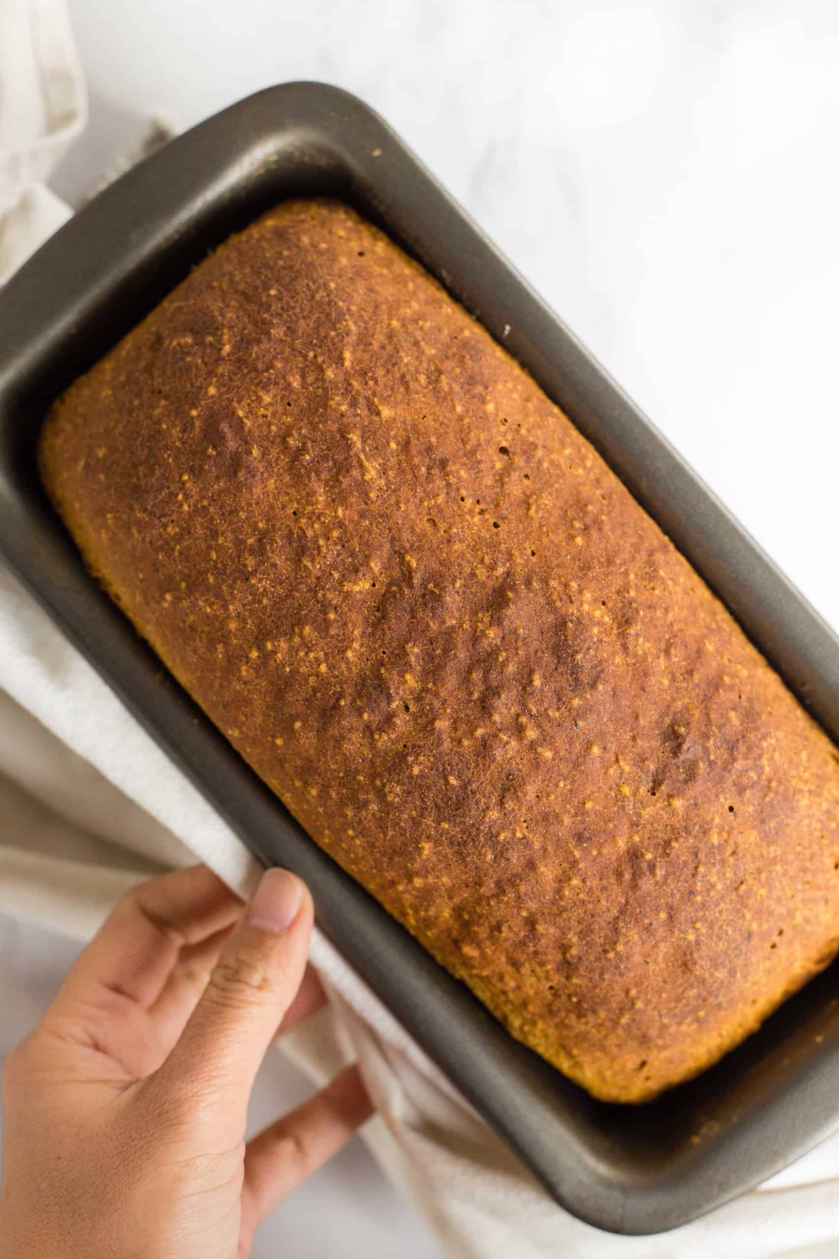 A freshly baked loaf of pumpkin yeast bread in metal pan.