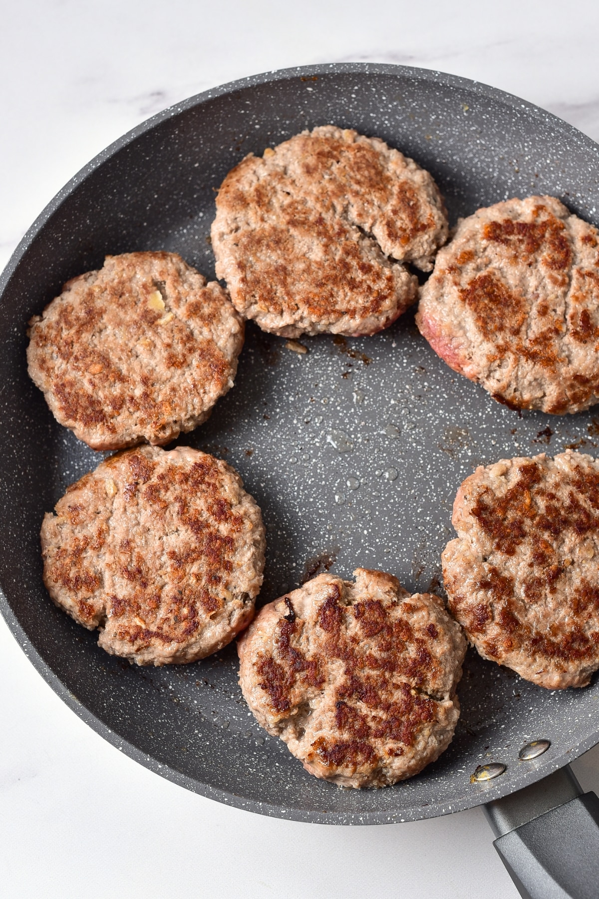 Cooked ground beef patties in skillet