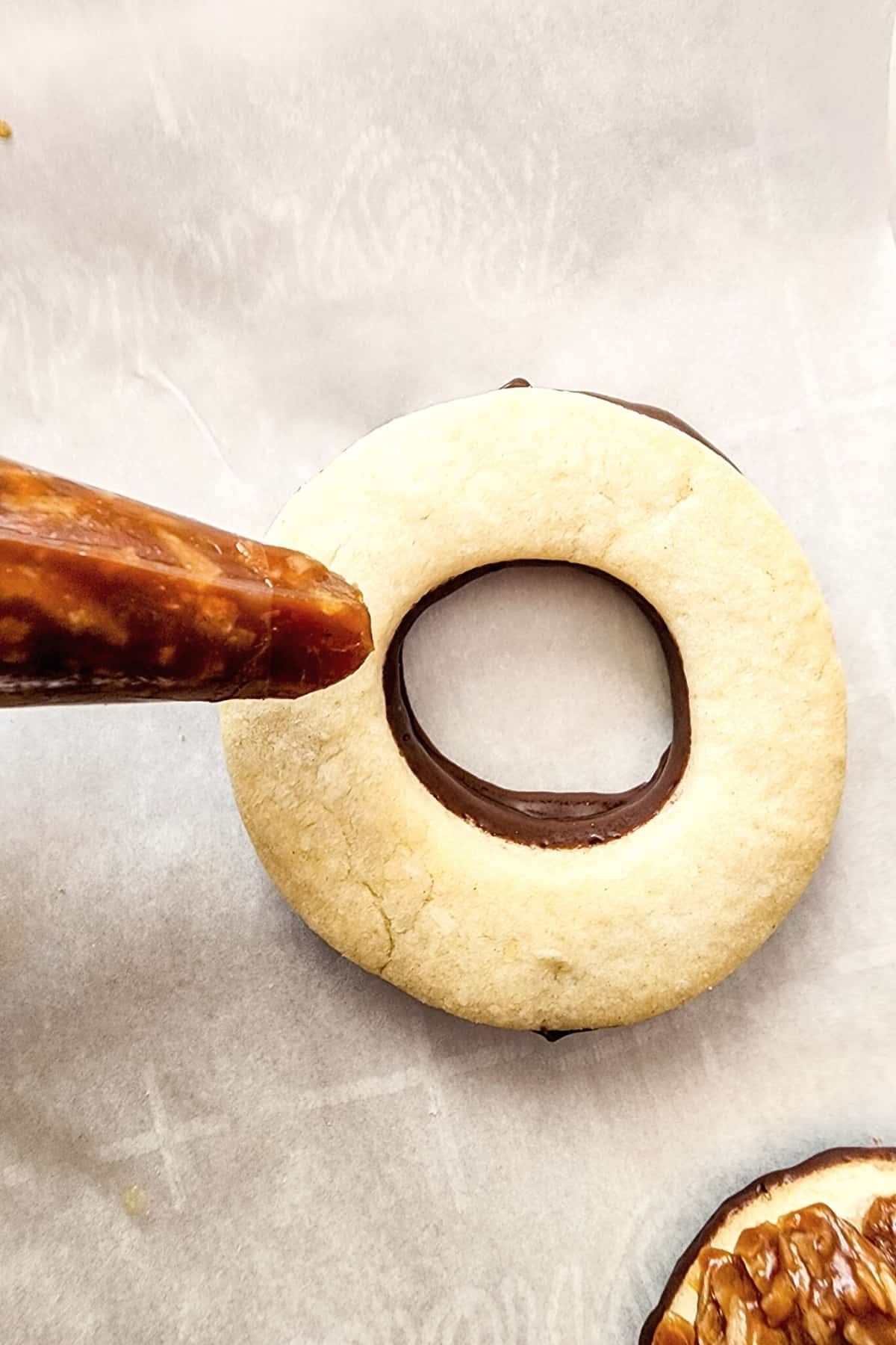 Piping caramel filling on top of cookie.