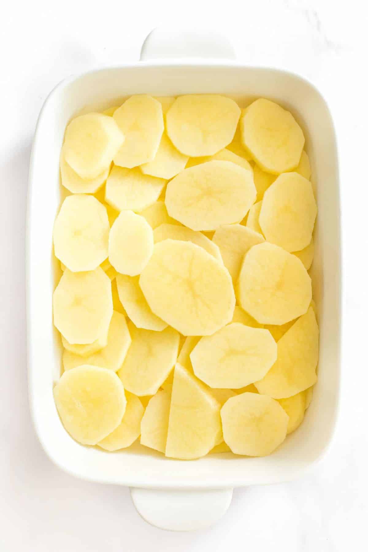Sliced potato rounds in casserole dish.