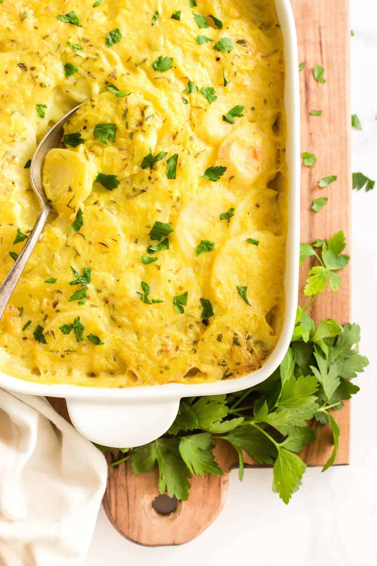 Top down view of scalloped potatoes on wooden board.