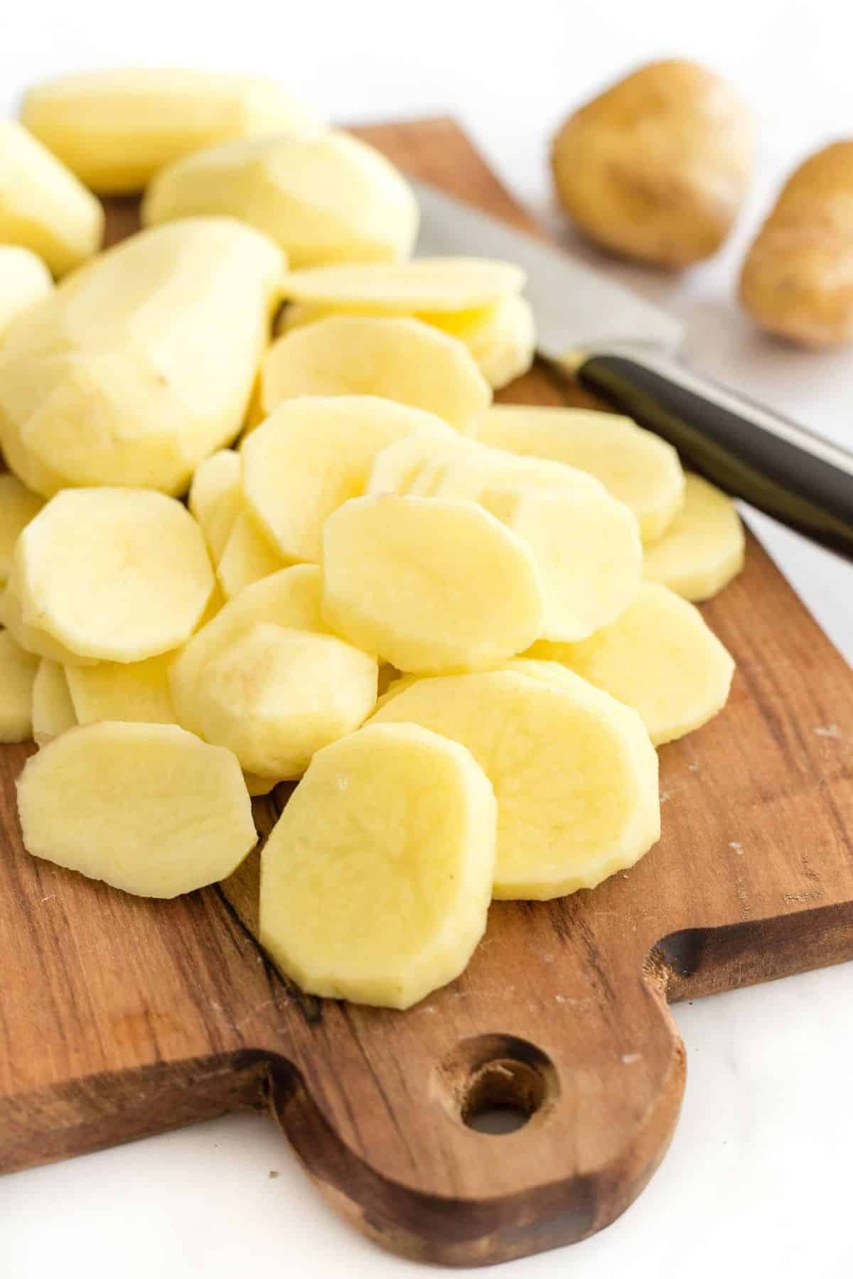 Sliced potato rounds on wooden board.