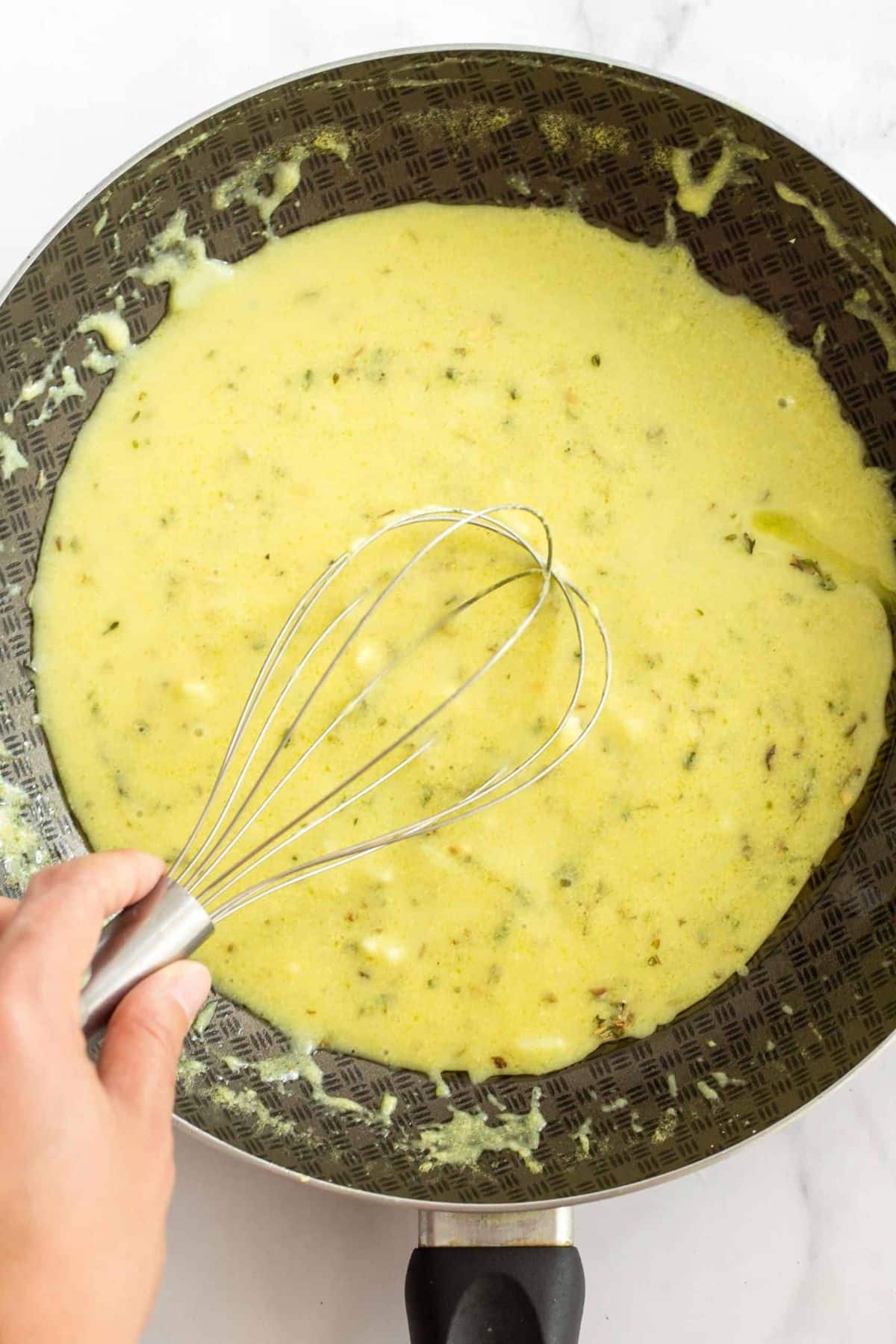Whisking pale yellow mixture in skillet.
