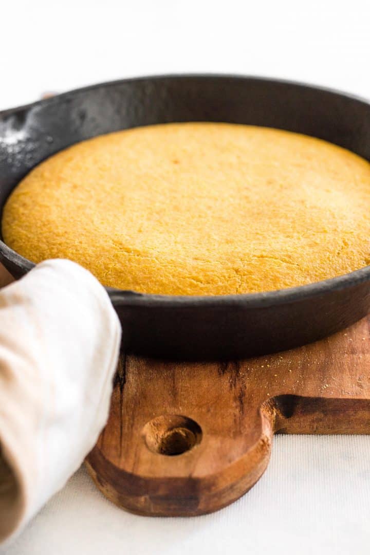 Freshly baked cornmeal in skillet on wooden board.