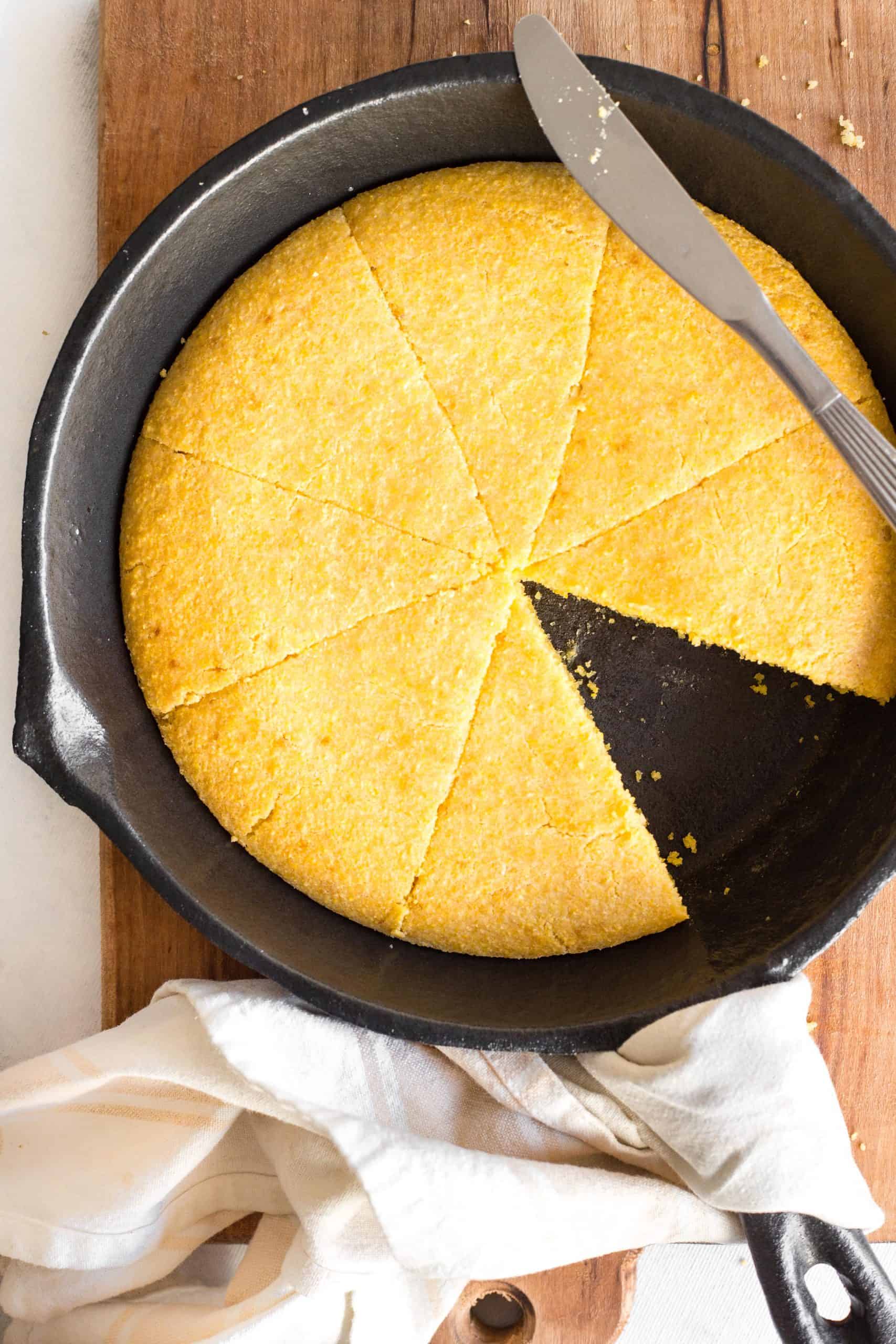 A cast iron skillet with sliced cornbread.