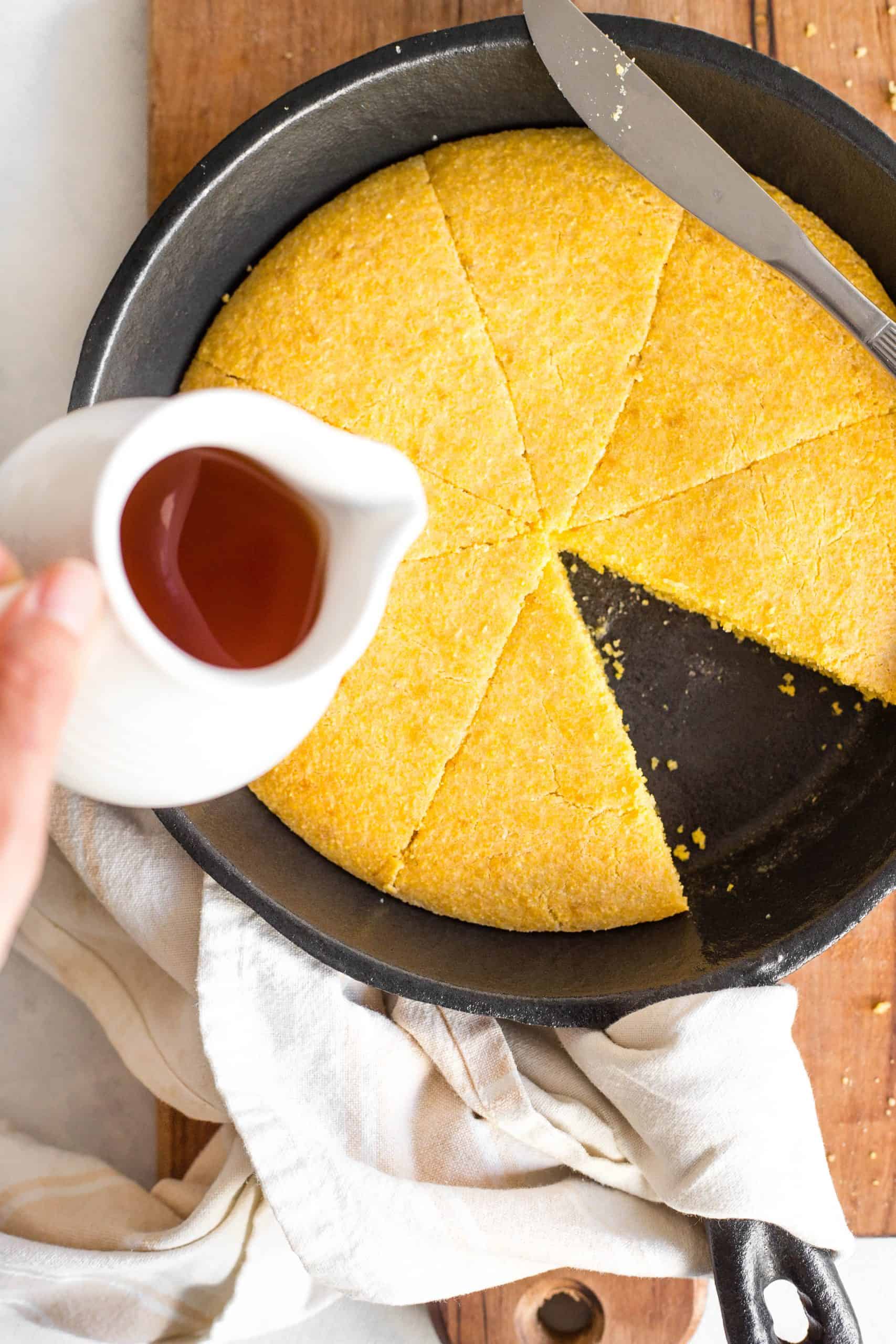 Pourding honey over gluten-free cornbread in a skillet.