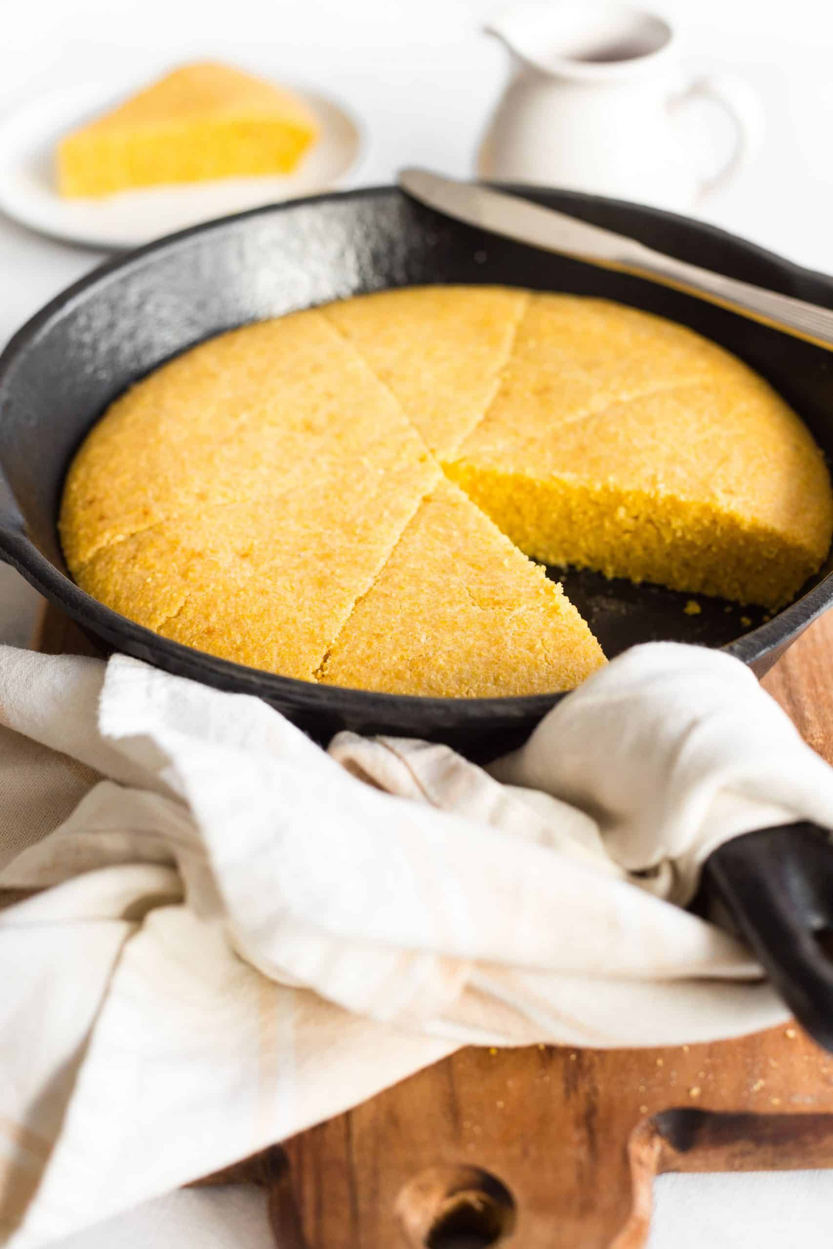 A skillet with cornbread on a wooden board.