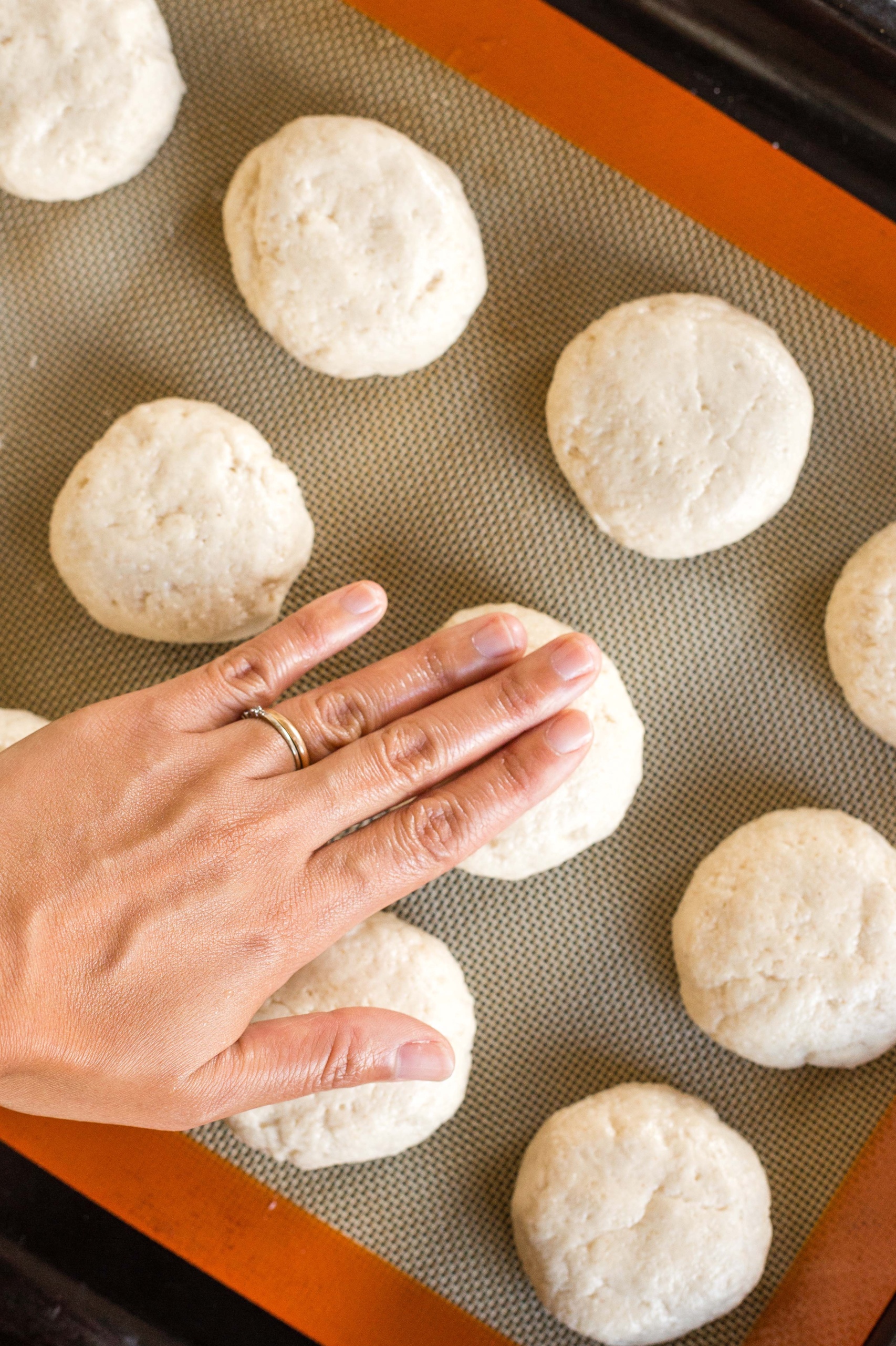 Using fingers to flatten balls of dough.
