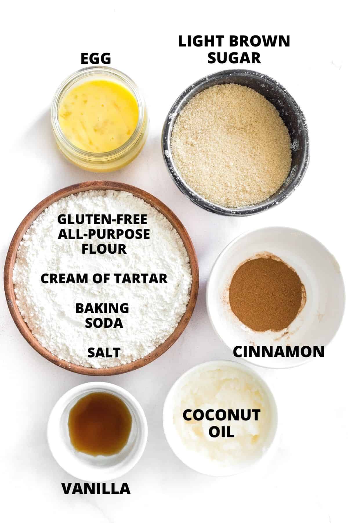 Labeled ingredients for a gluten-free snickerdoodle cookies recipe on a marble board.