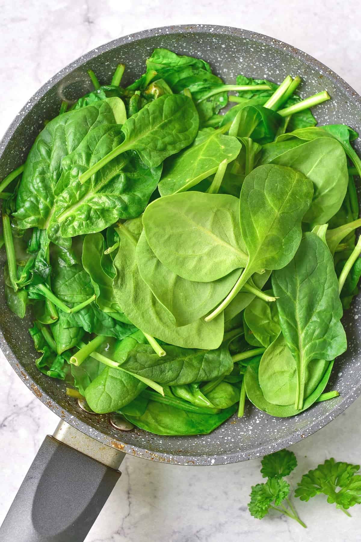 Fresh spinach leaves in a skillet.