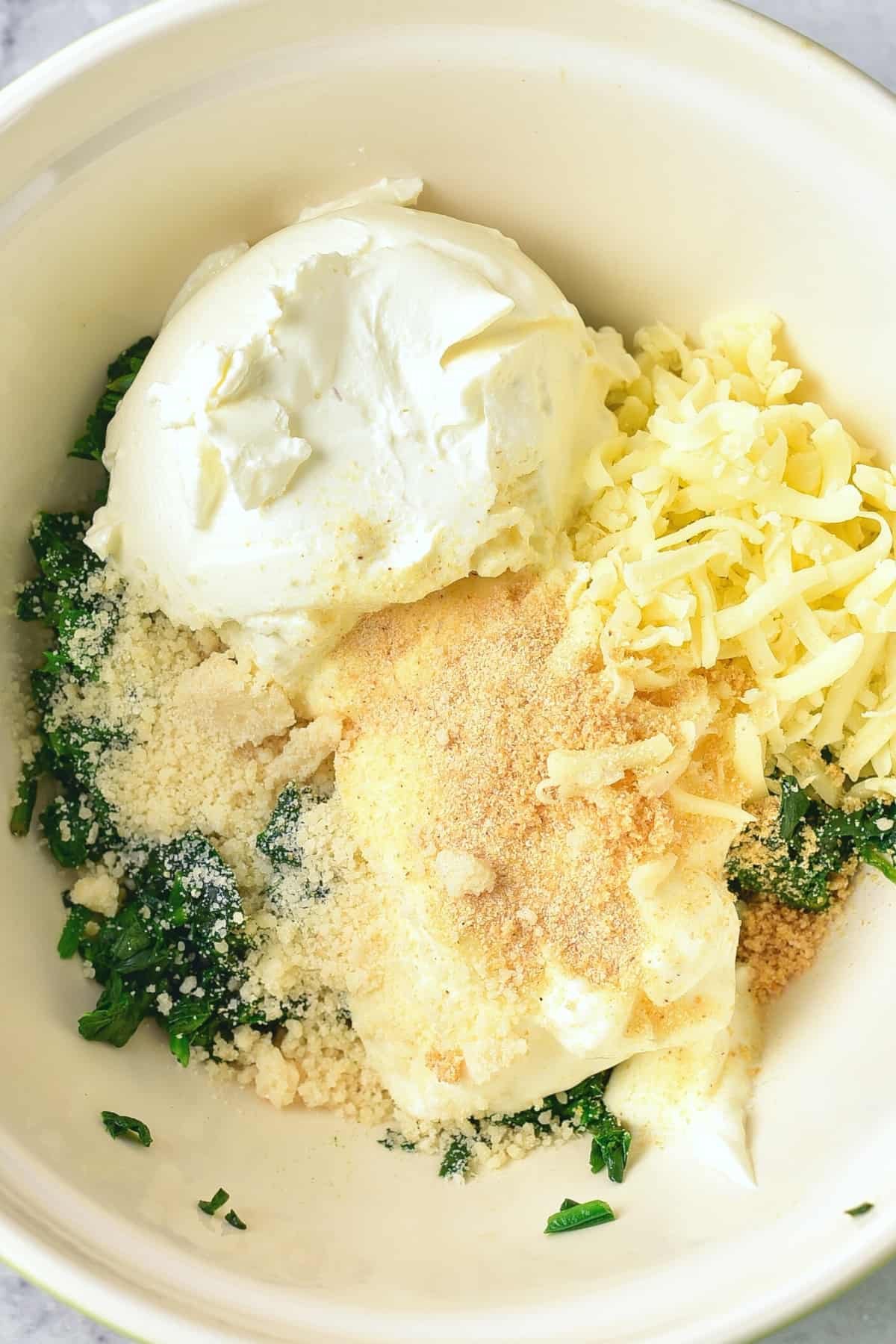 Cooked spinach, cream cheese, mozzarella cheese in a bowl.