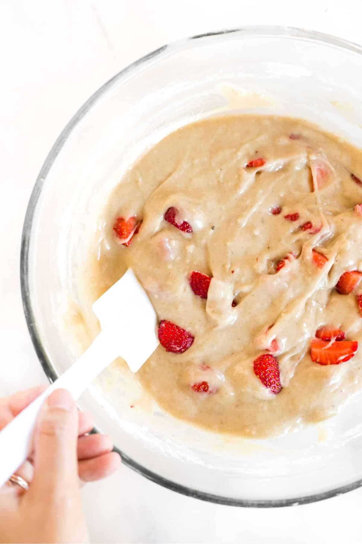 Folding fresh strawberries into gluten-free muffin batter.