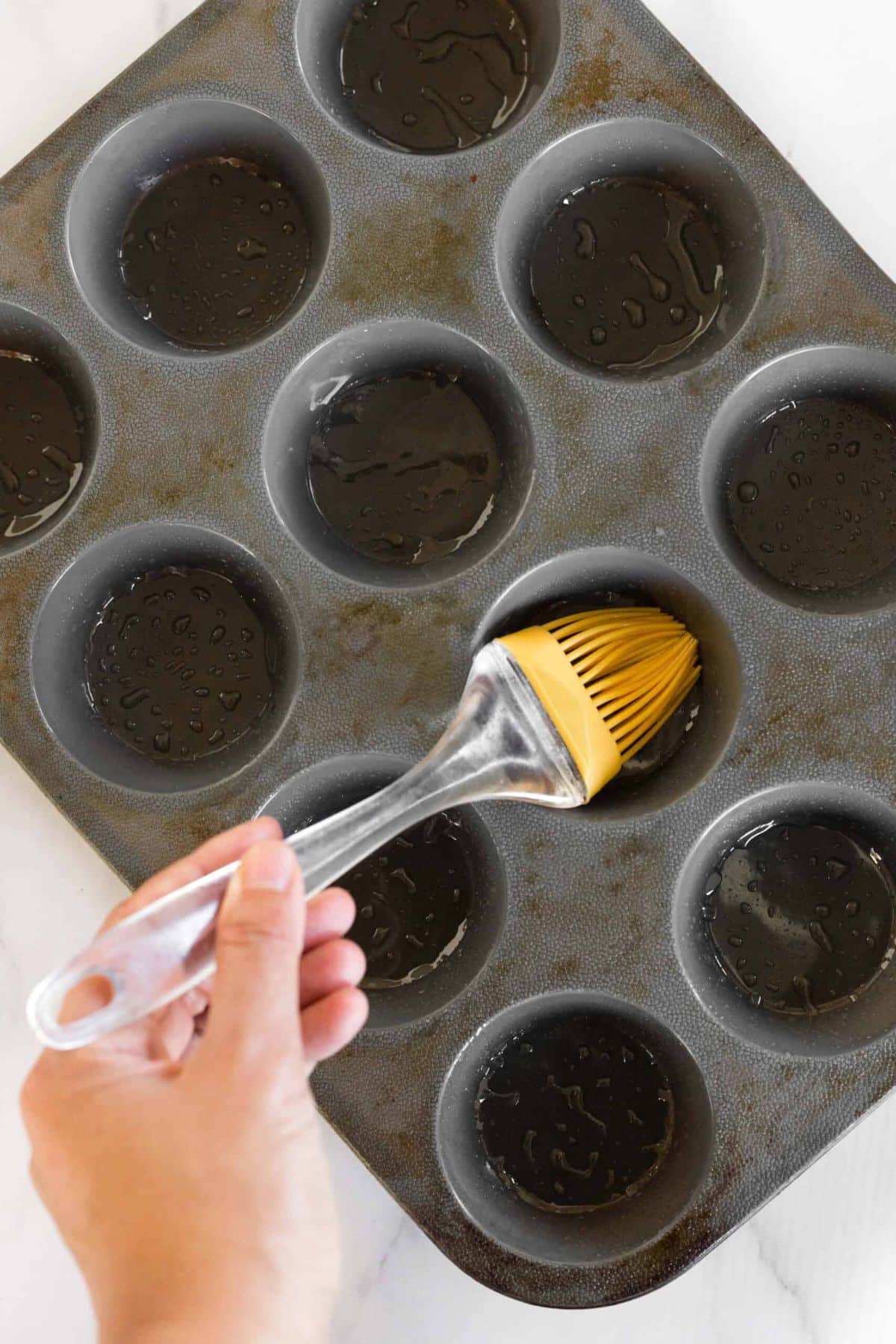 Using silicon brush to grease silicon muffin mold.