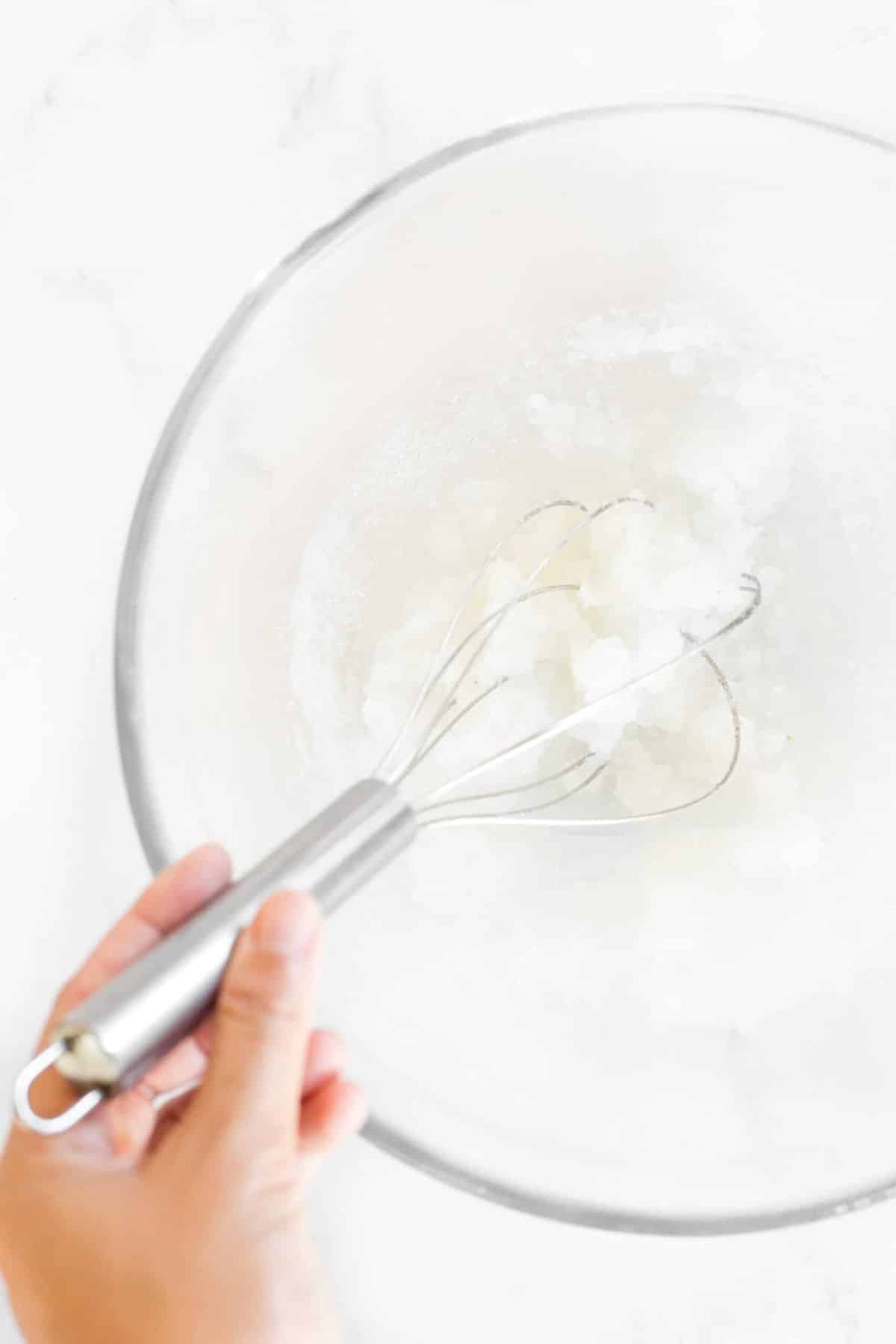 Mixing oil and sugar in glass bowl.