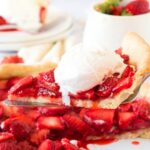 Holding up a slice of strawberry pie topped with ice cream