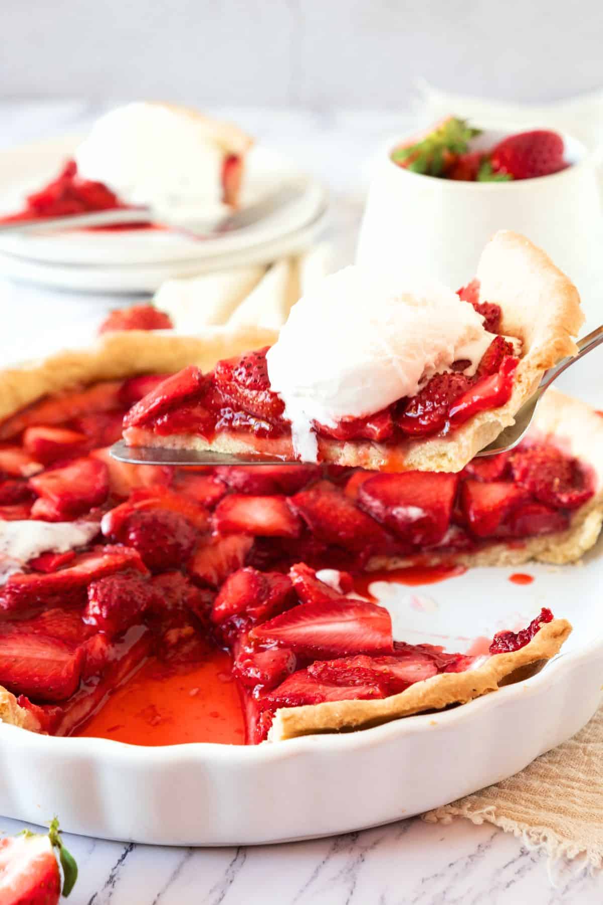 Holding up a slice of gluten-free fresh strawberry pie from pie plate.