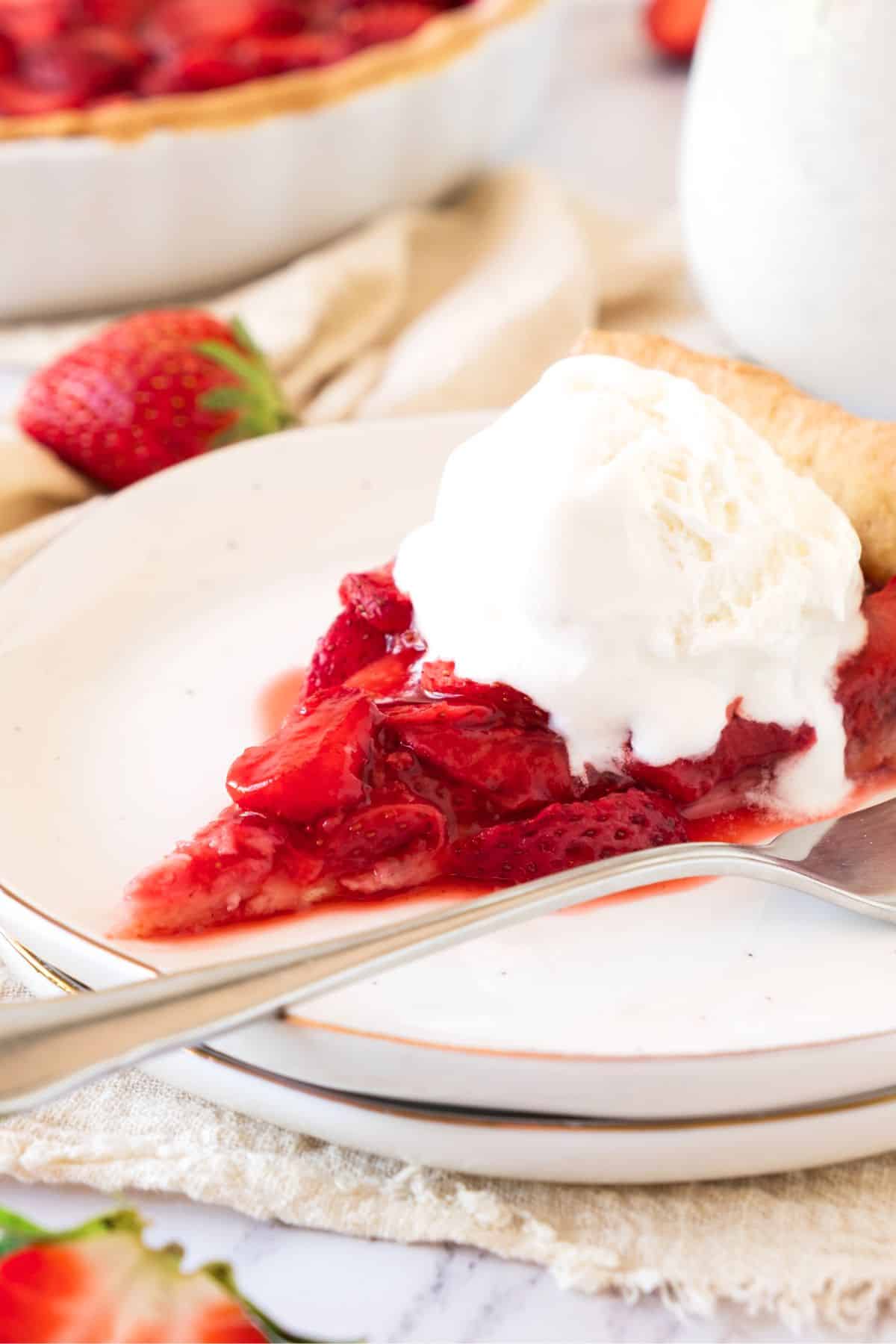 A slice of strawberry pie topped with ice cream