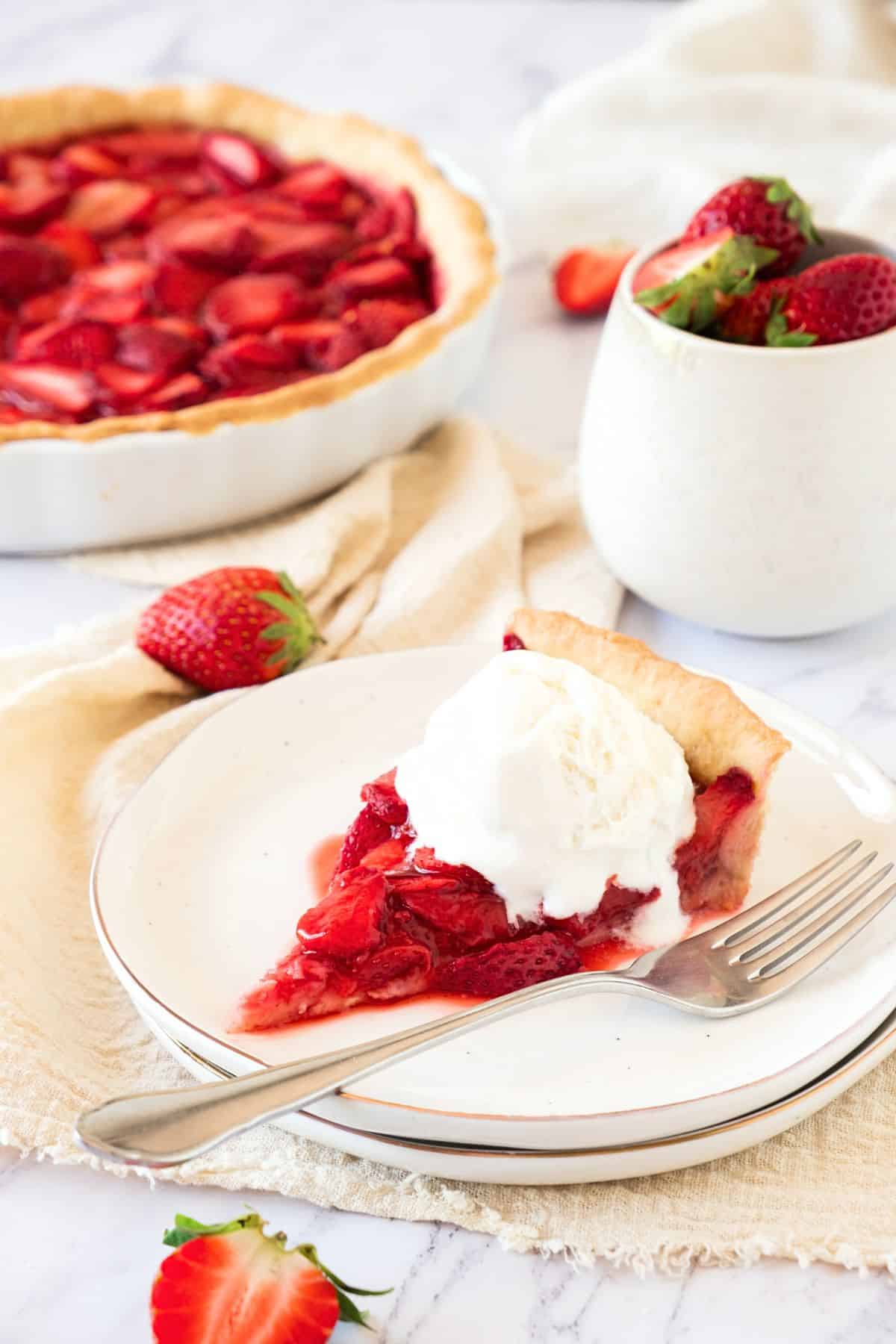 A plate of ice cream topped strawberry pie.