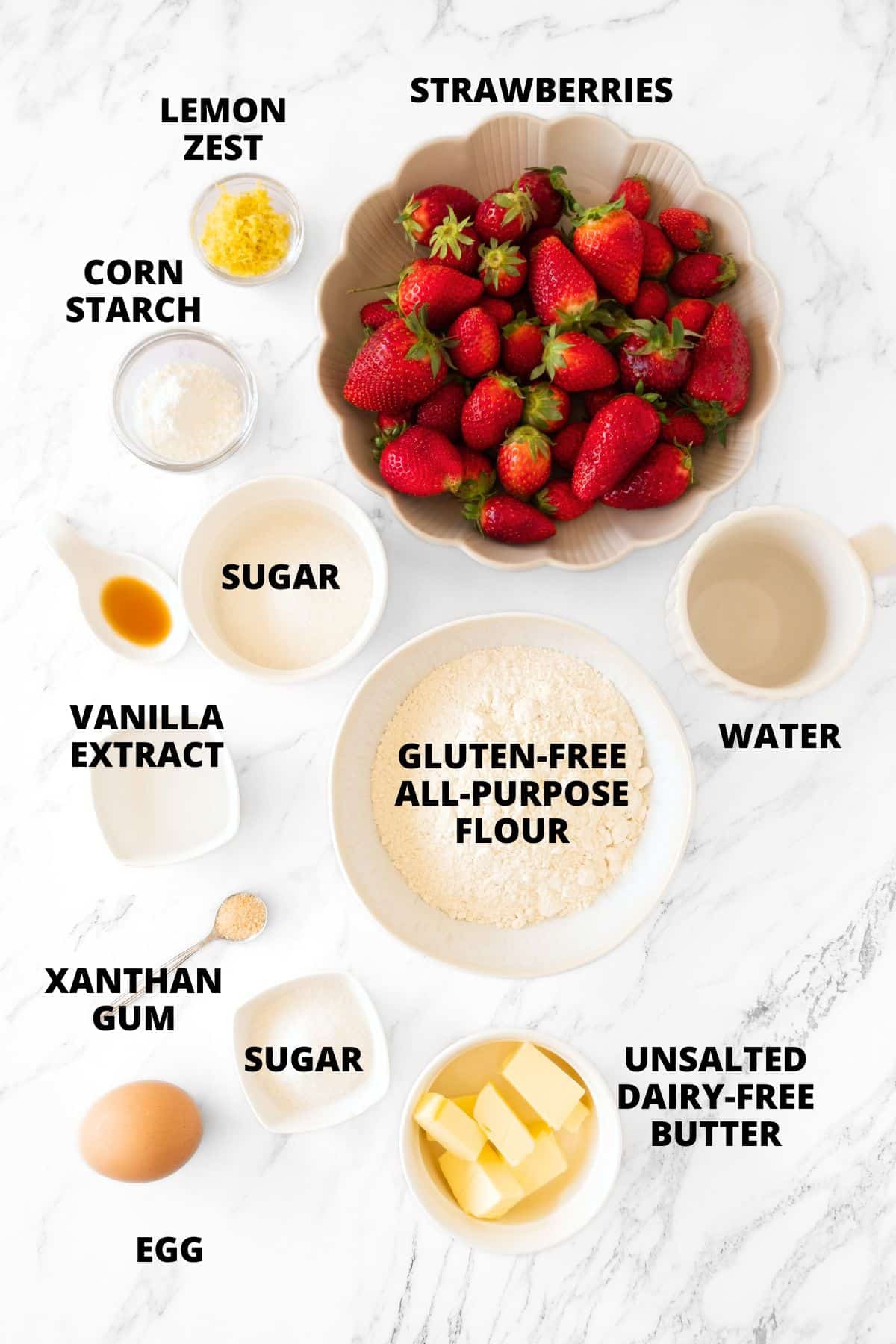 Ingredients for gluten-free strawberry pie recipe laid out on marble board.