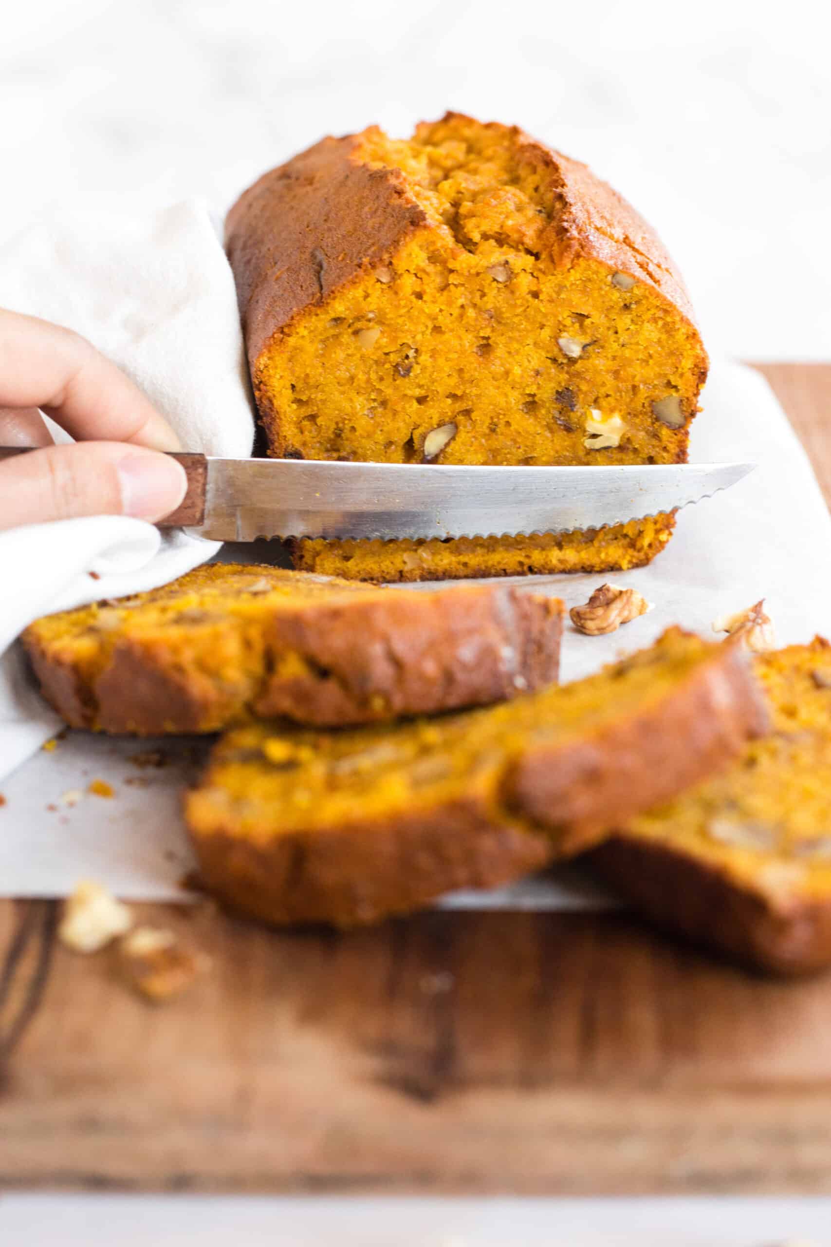 Slicing into a loaf of gluten-free sweet potato quick bread.