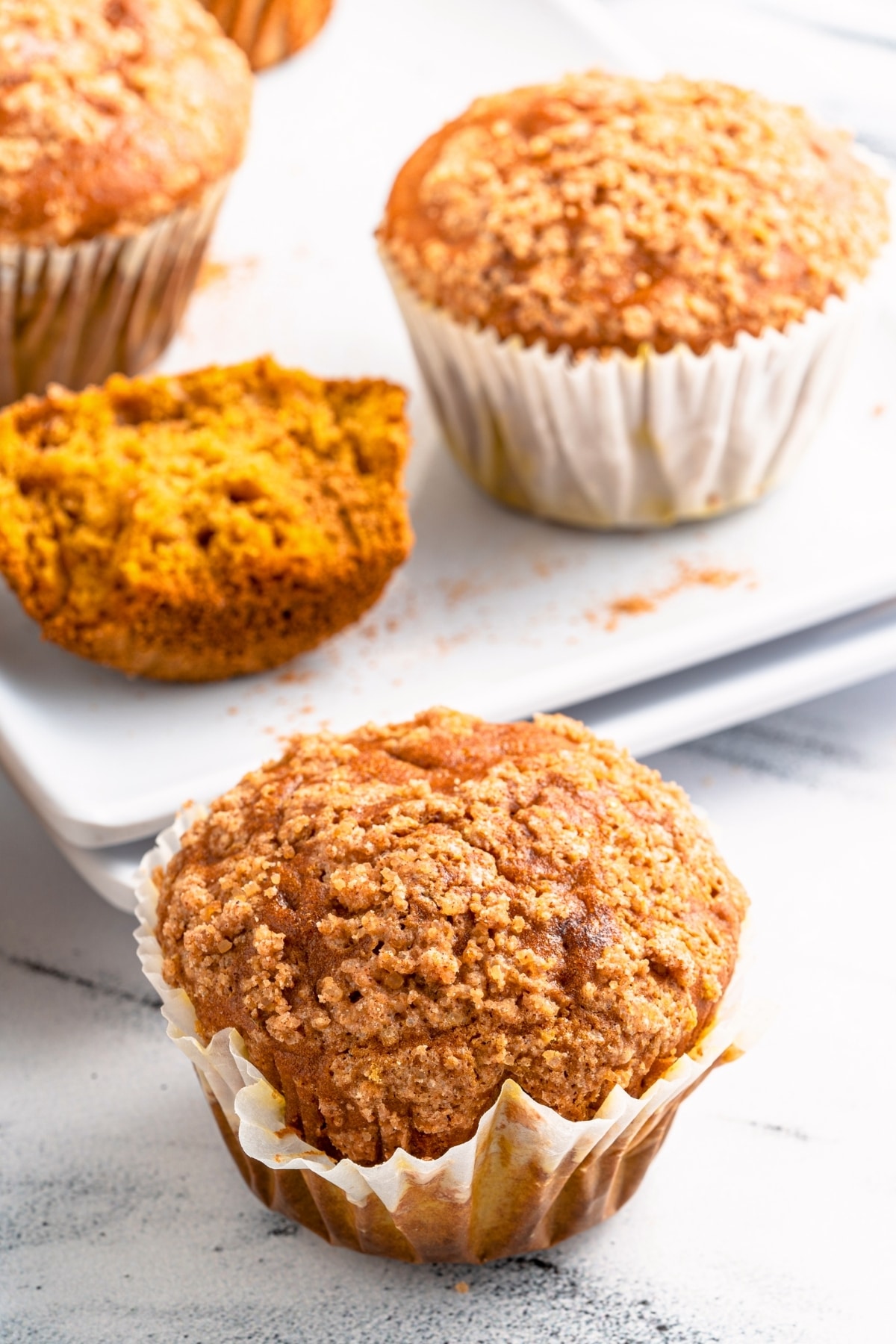Up close shot of sweet potato muffin in front of a plate of muffins.