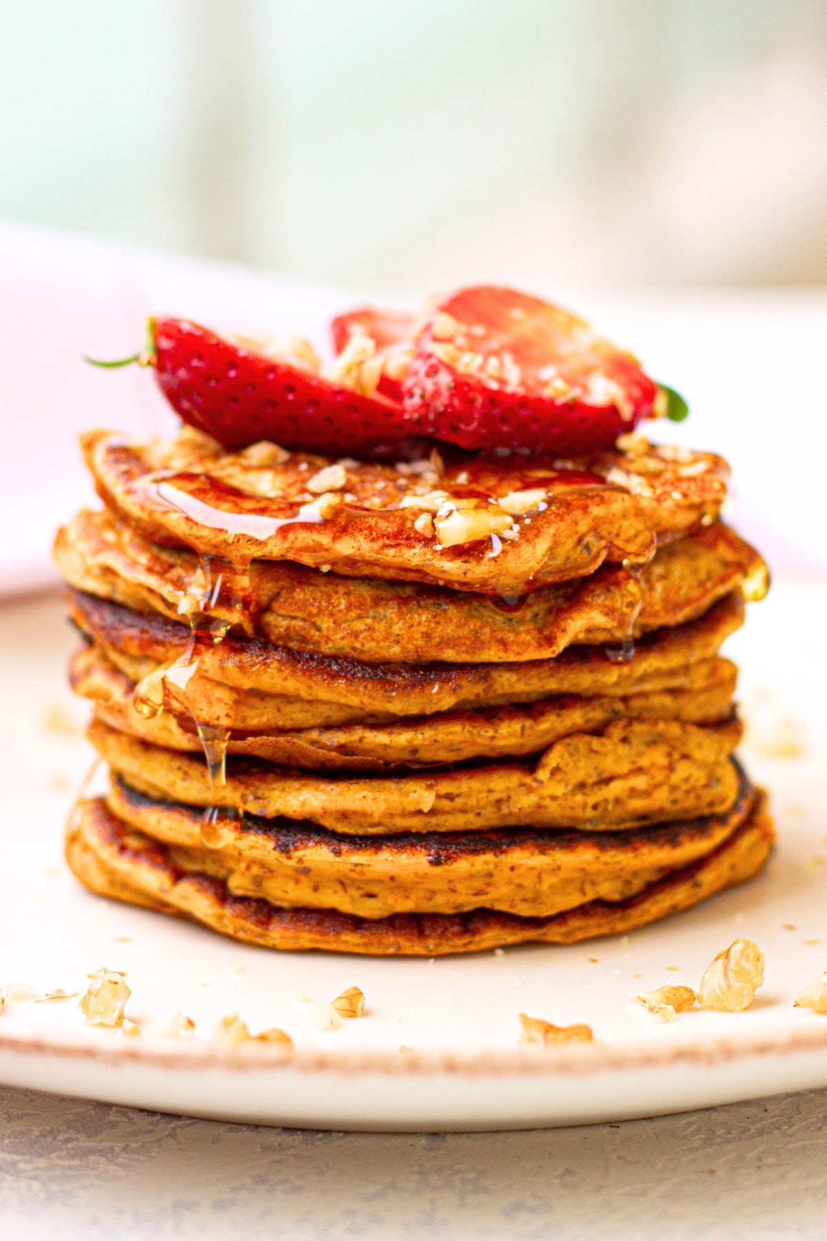 A stack of gluten-free sweet potato pancakes topped with strawberries.