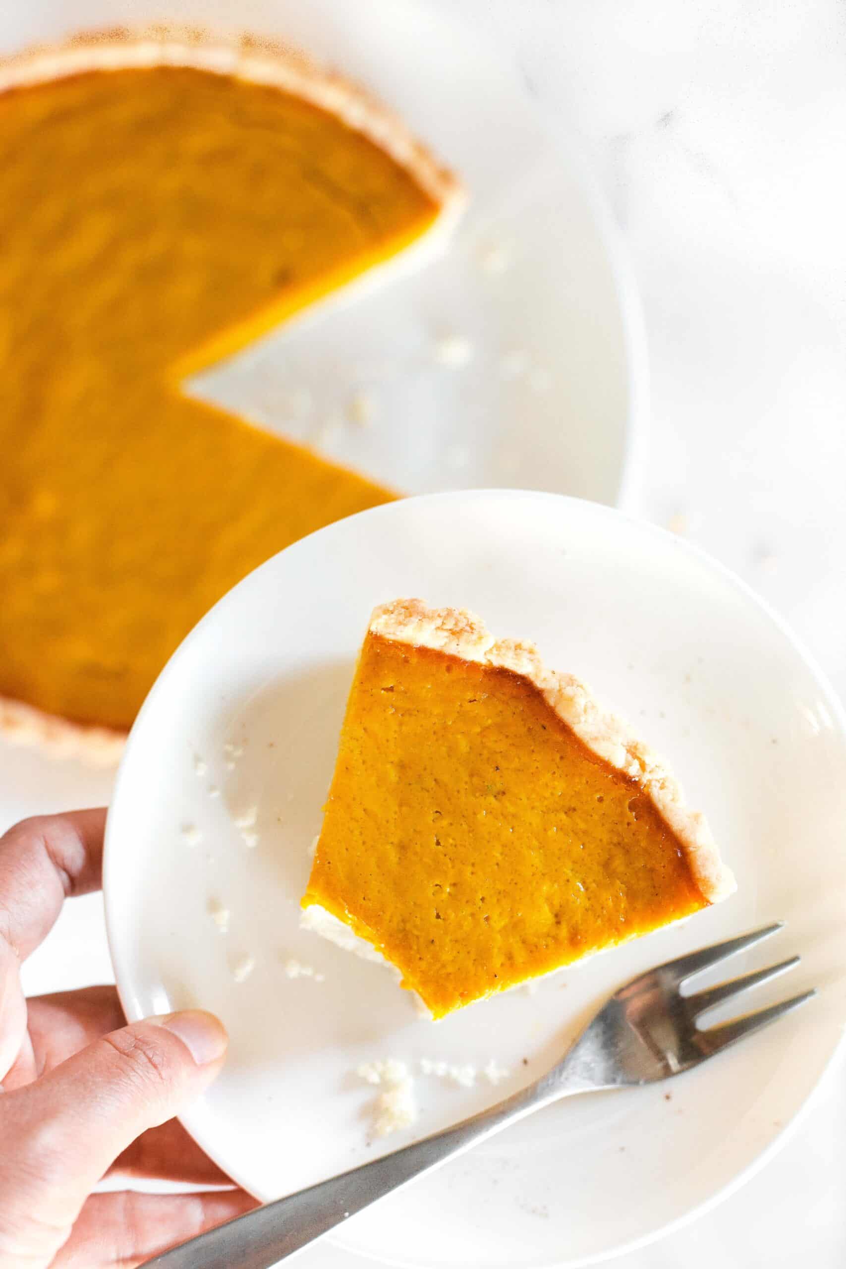 Holding up a plate with a slice of half-eaten gluten-free sweet potato pie.