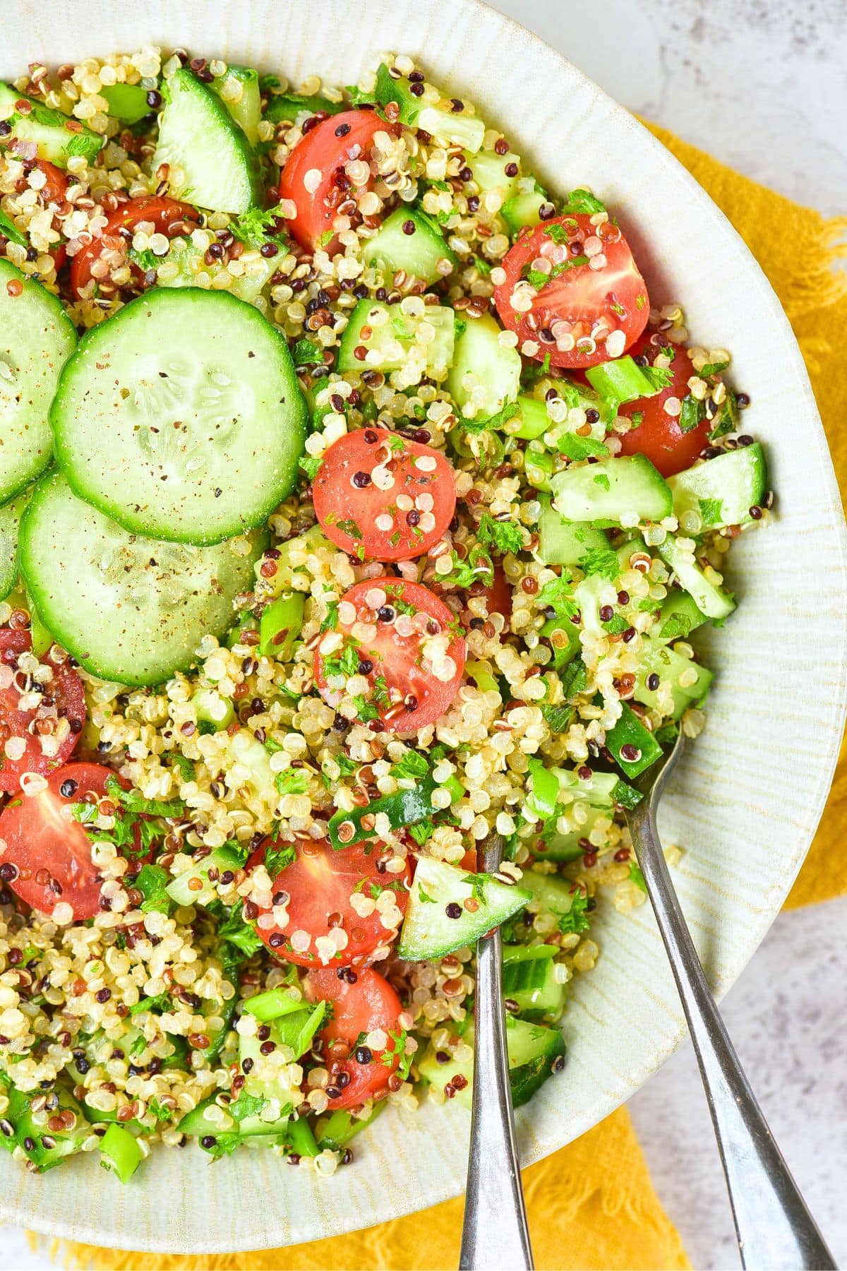 Quinoa Tabbouleh Salad (Gluten-Free, Vegan) Up close view a bowl of quinoa tabbouleh salad topped with cucumber slices.