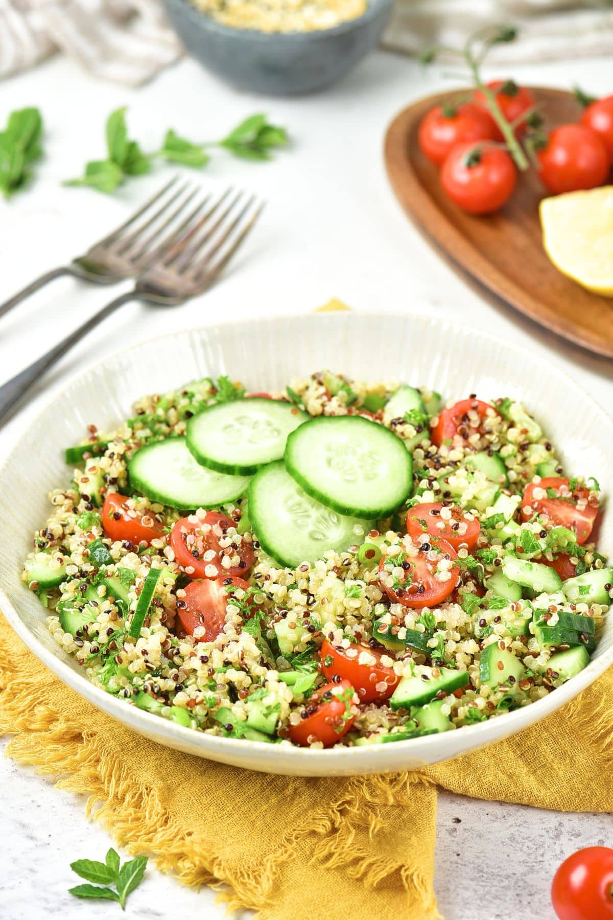 Quinoa Tabbouleh (Gluten-Free, Vegan) A bowl of quinoa tabbouleh on a yellow kitchen towel.