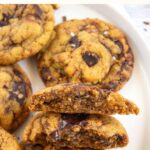 Top down view of half-eaten chocolate chip tahini cookies on plate.