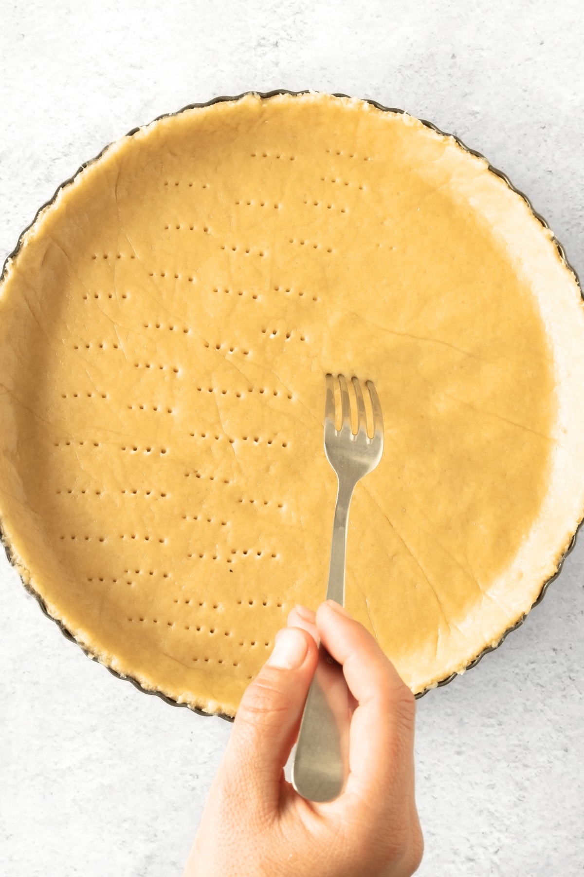 Using a fork to prick holes in tart crust dough.