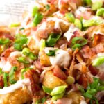 Up close view of tater tots garnished with bacon and green onions.