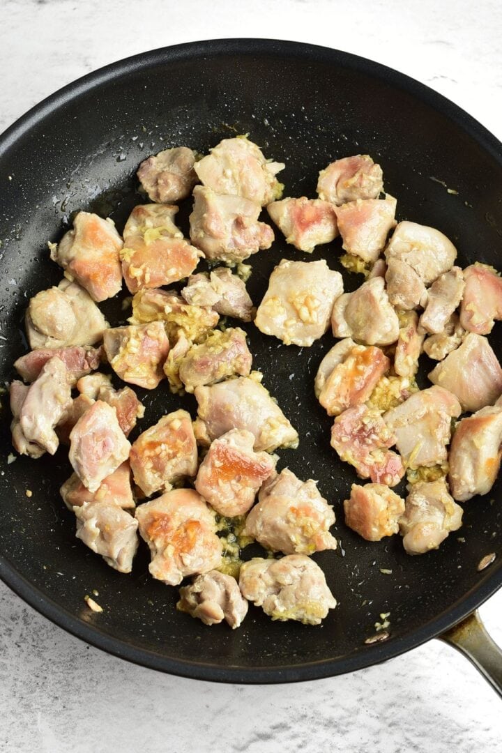 Cooking chicken pieces with minced garlic and grated ginger