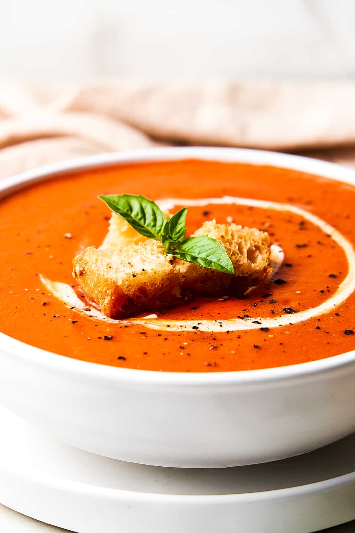 Up close shot of a bowl of gluten-free tomato soup with croutons and basil.