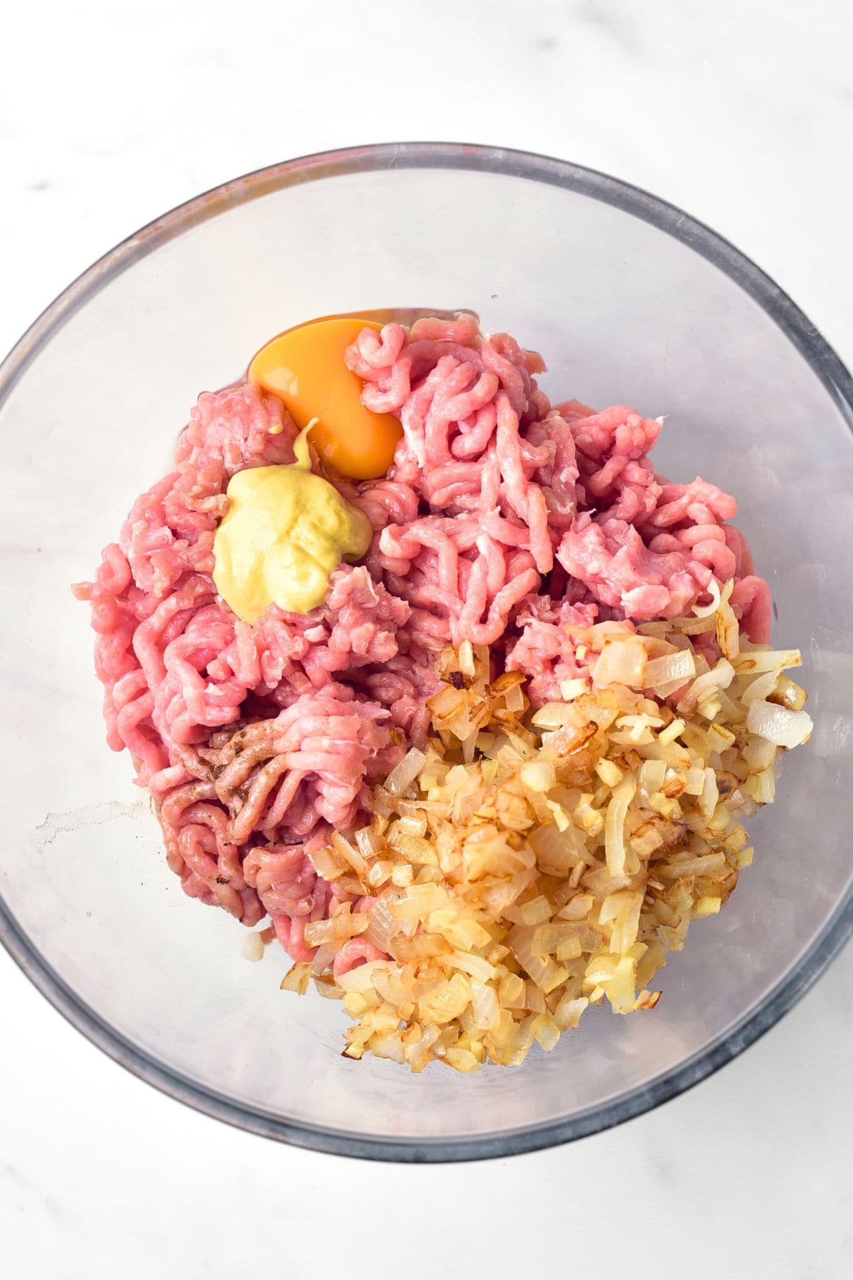 A bowl of ground turkey meat, caramelized onions, mustard and sauce.