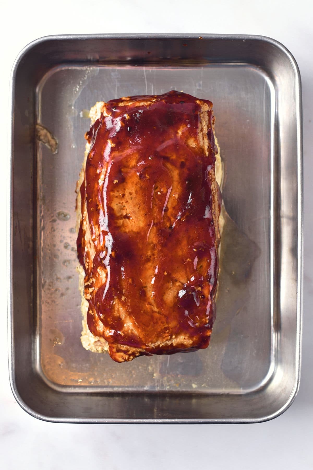 Glazed meatloaf in baking pan.