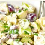 A bowl of grapes, apples, celery in dressing.