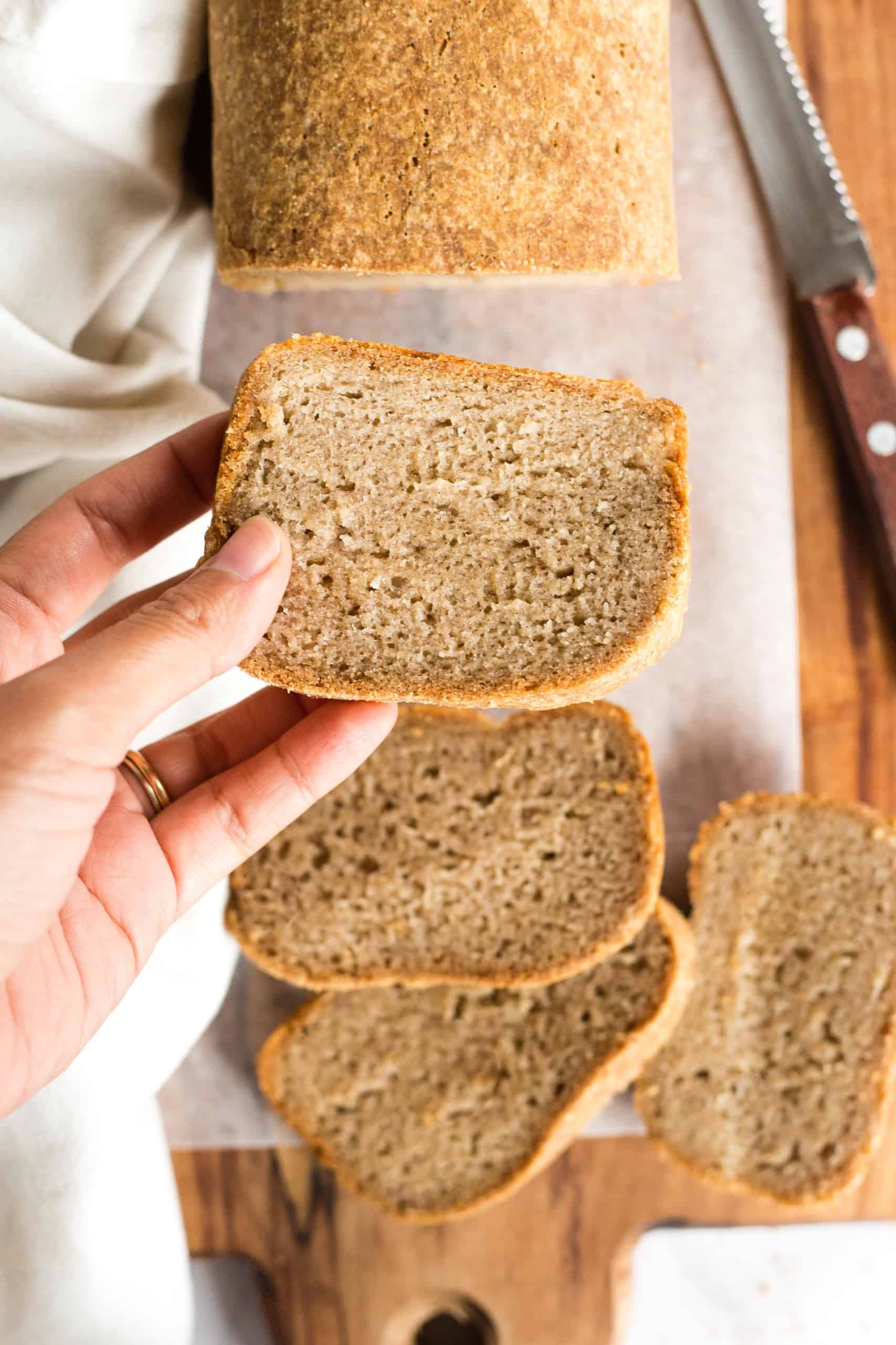 Holding up a slice of gluten-free wholegrain bread.
