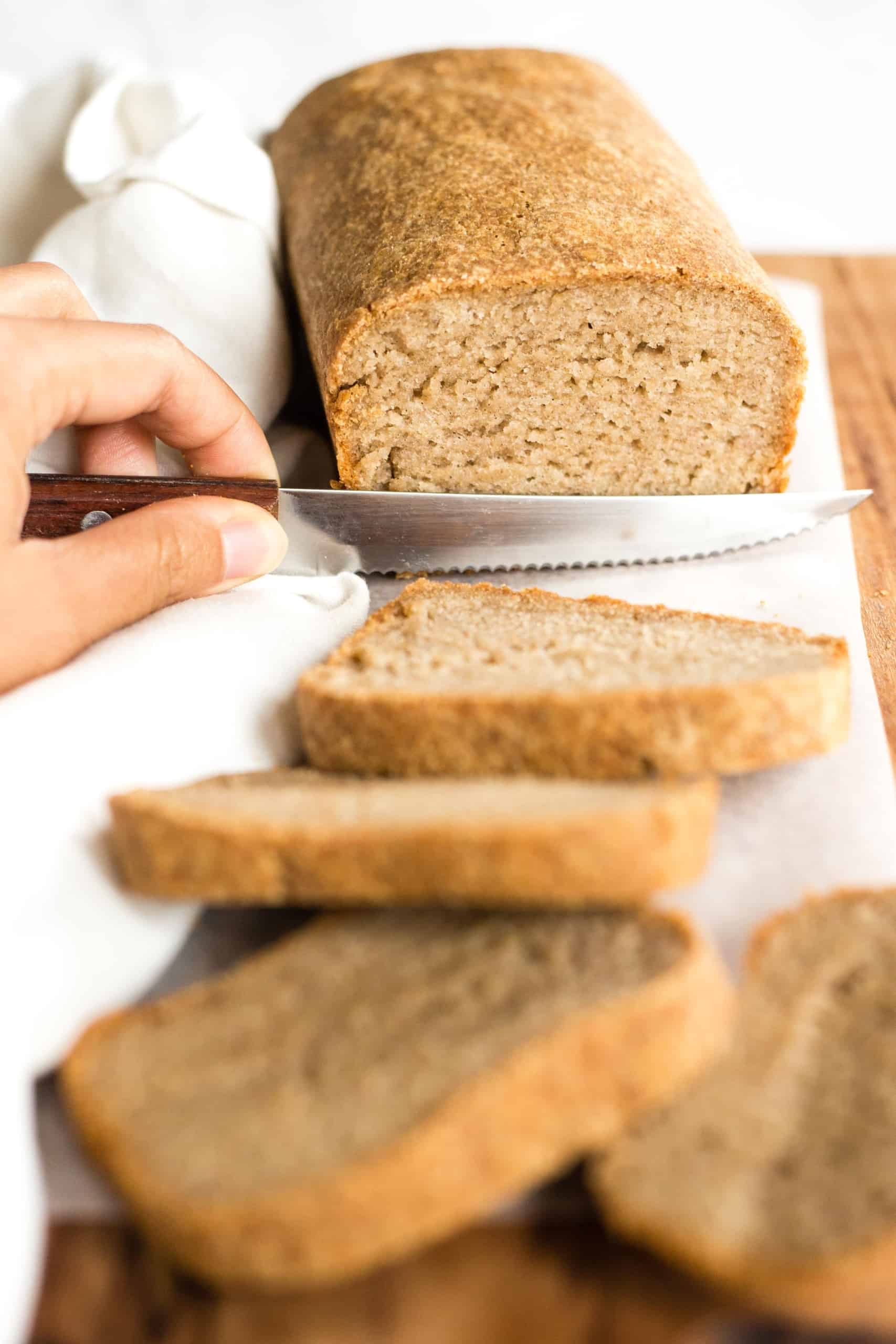 Slicing into a loaf of gluten-free brown bread.