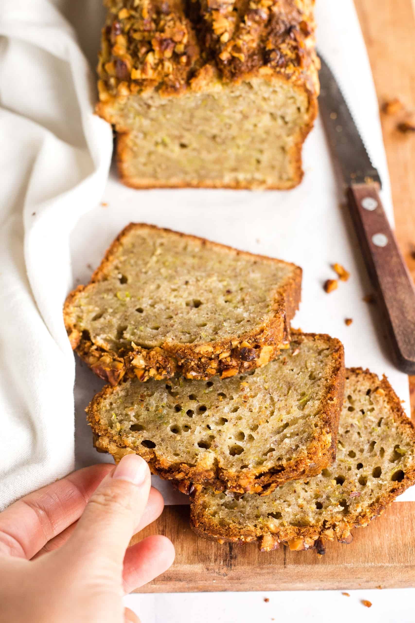 Hand reaching for a slice of zucchini bread.
